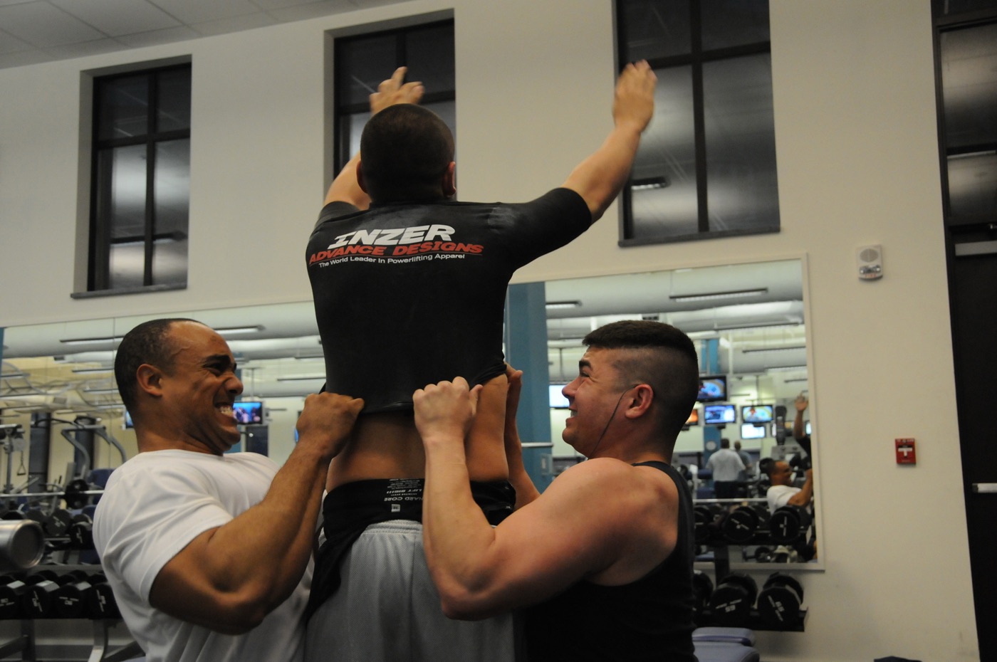 Two airmen helping a third lifter into an Inzer bench shirt at a powerlifting meet